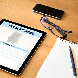Dental insurance form on tablet next to notepad