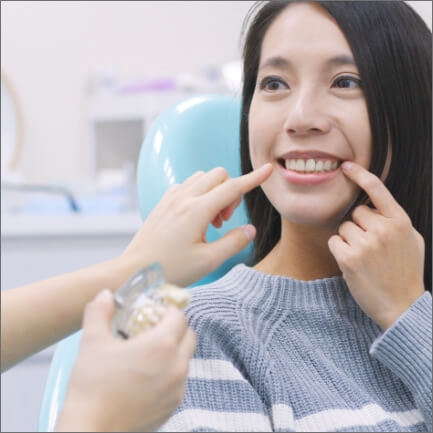 Woman pointing to her smile after teeth in a day tooth replacement