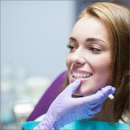 Dentist examining dental patient's smile after dental crown restoration