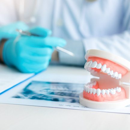 A closeup of dentures on a table next to a dentist