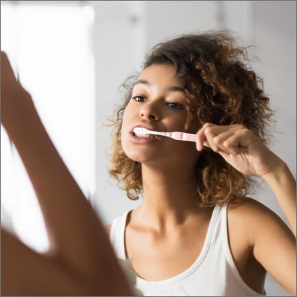 Woman brushing teeth to prevent dental emerencies