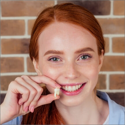 Young woman holding wisdom tooth after extraction