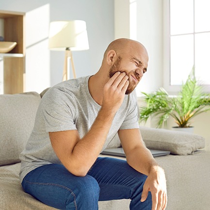 a man holding his cheek due to an injured tooth