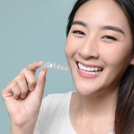 Smiling woman holding an Invisalign tray