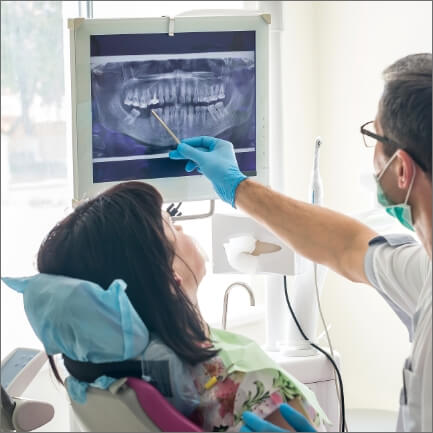 Dentist looking at digital x rays on computer screen