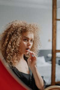 Woman brushing her teeth and looking in mirror