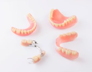 2 sets of full and partial dentures on a white background
