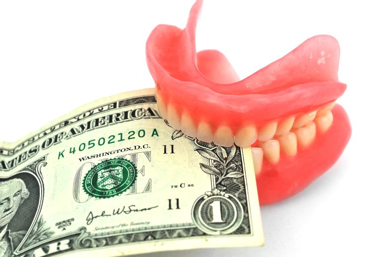 A pair of dentures biting a dollar bill